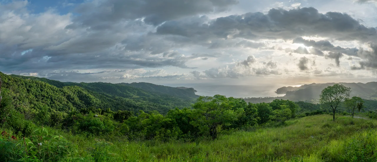 Green hills and the bay near Tarimbang beneath a cloudy sky