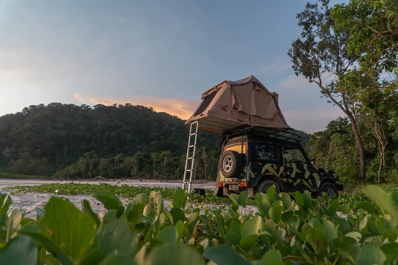 Camouflage Jeep with a rooftop tent in low coastal light