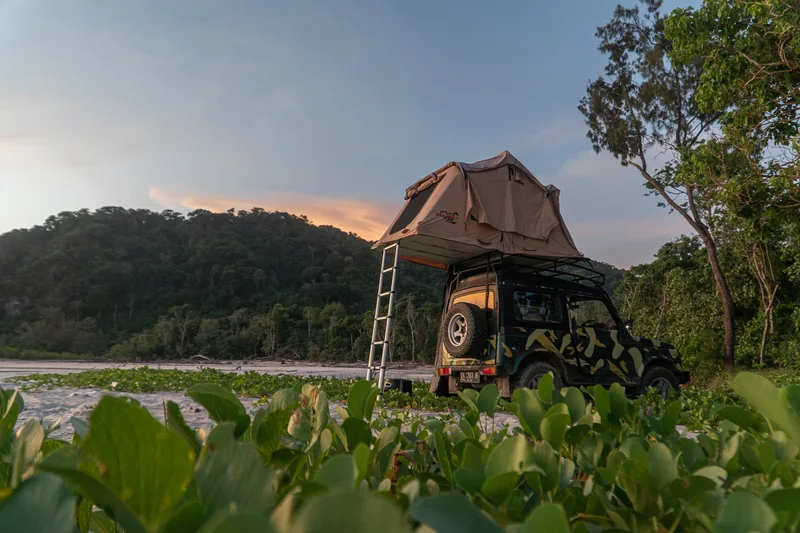 Camouflage Jeep with a rooftop tent in low coastal light
