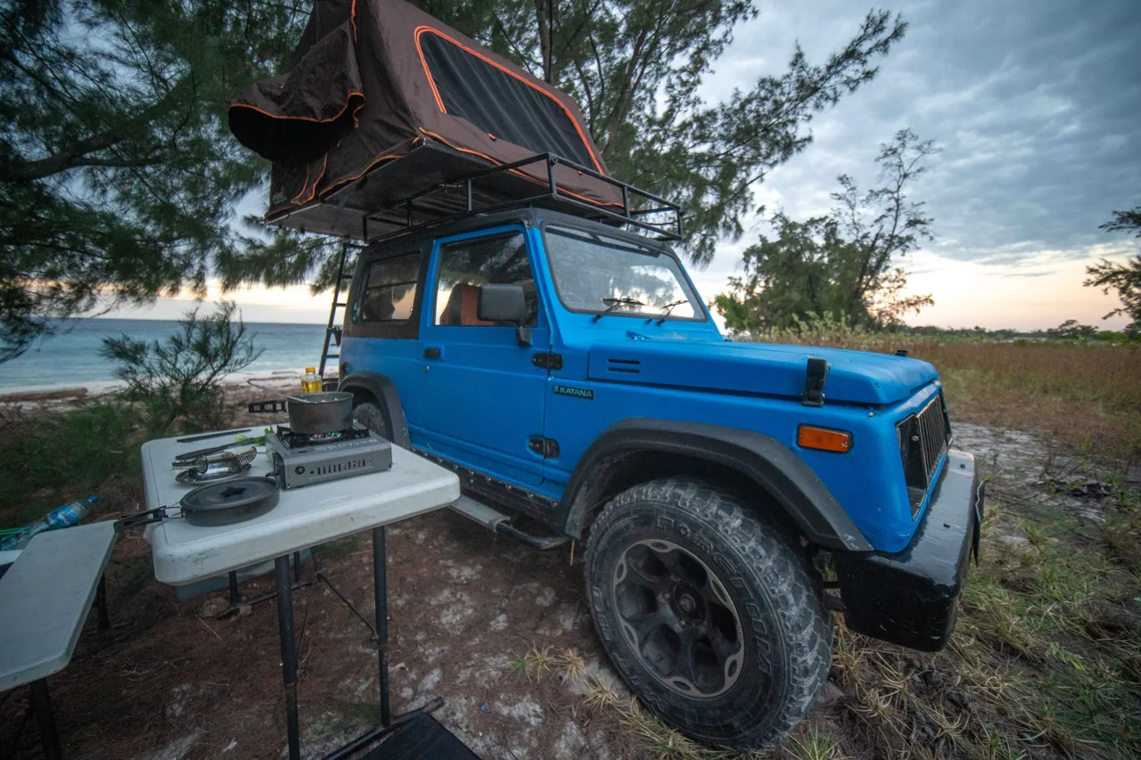 Blue Jeep and rooftop tent beside a camping table