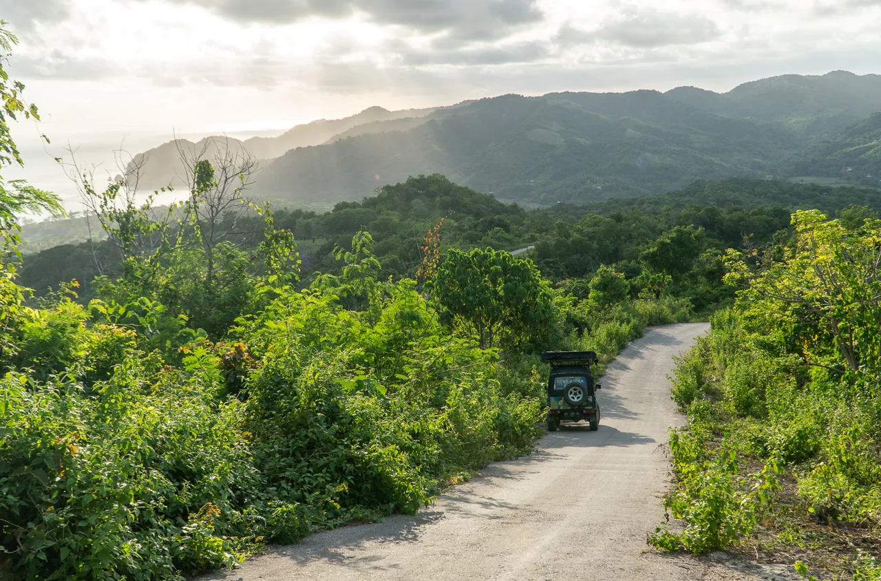 A RentSumba Jeep on a winding road through a green island landscape