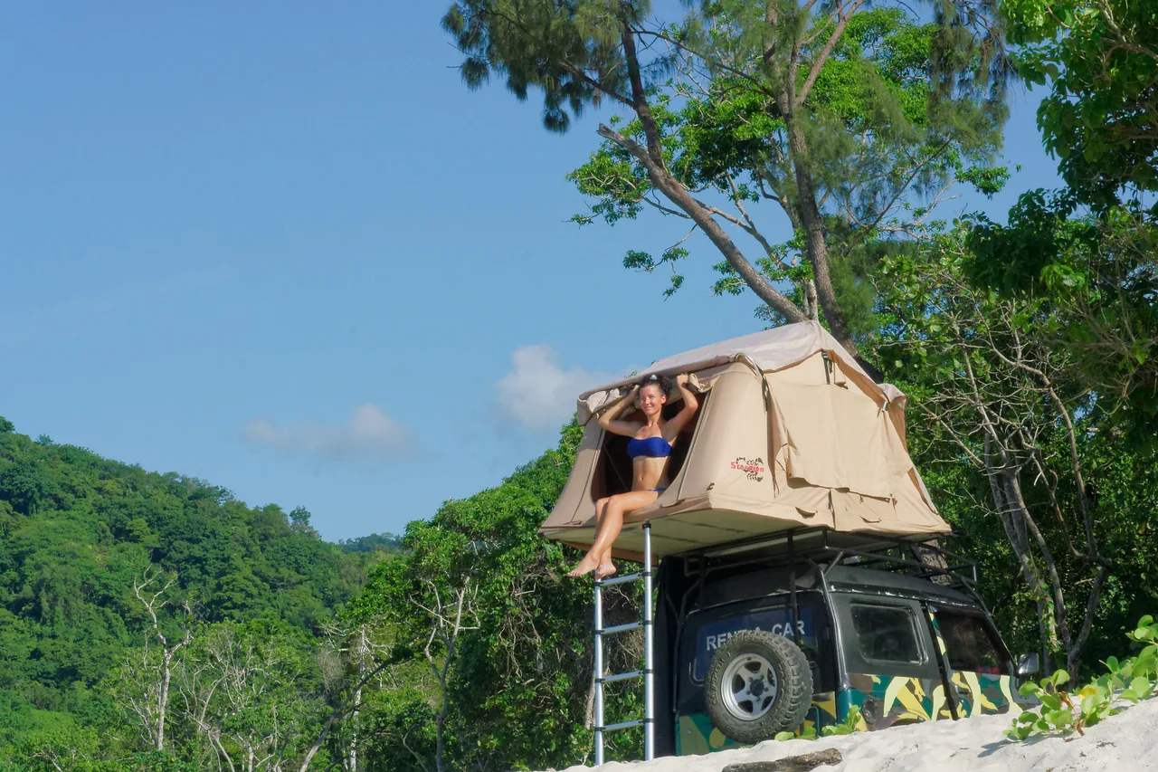 Traveller resting in the rooftop tent on the vintage Jeep